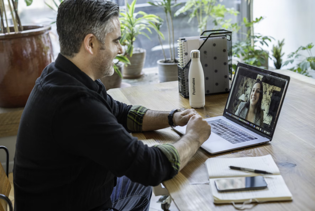 Man sitting at a computer talking with a woman through a virtual web meeting call